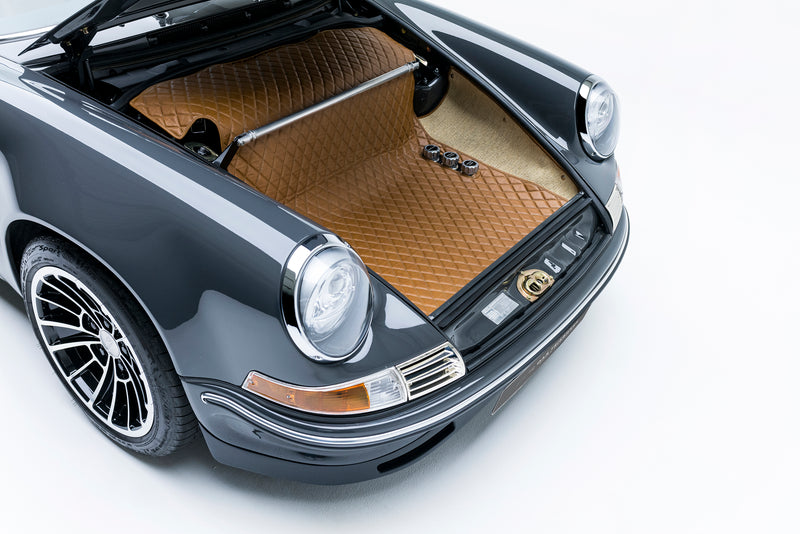 Close-up of a Triebwerk F3.6 frunk open with a brown floor mat on a white background