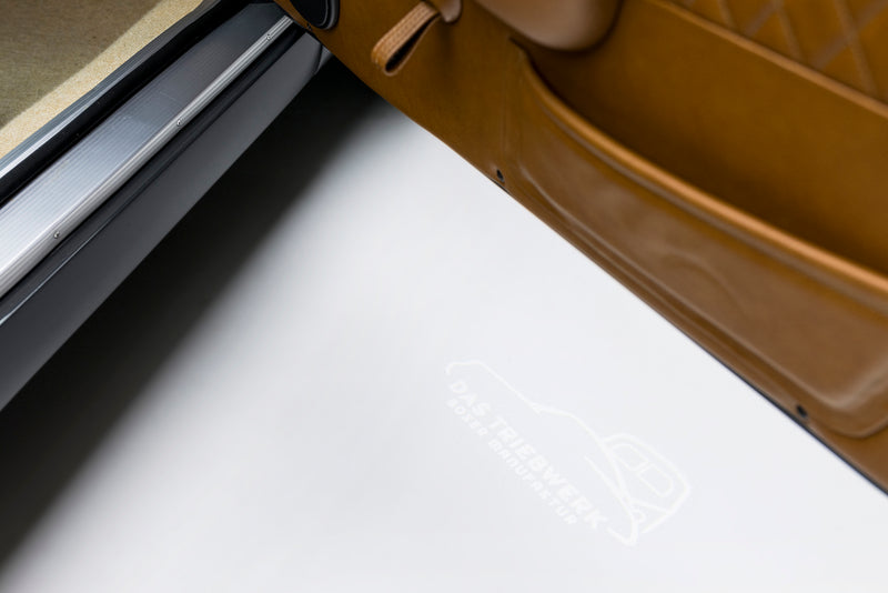 Close-up of a Gray Triebwerk F3.6 door with an illuminated Triebwerk logo on a white floor.