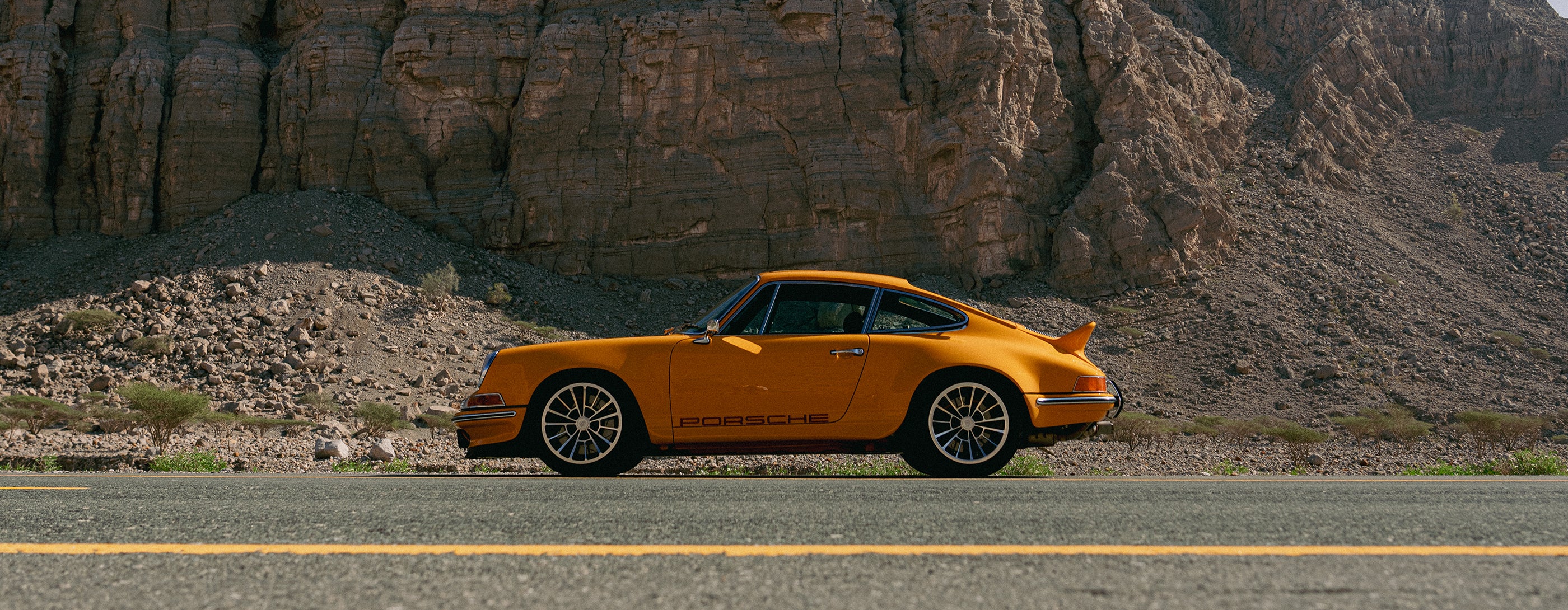 Yellow Triebwerk F4.3 Porsche 911 on a road with a mountain landscape