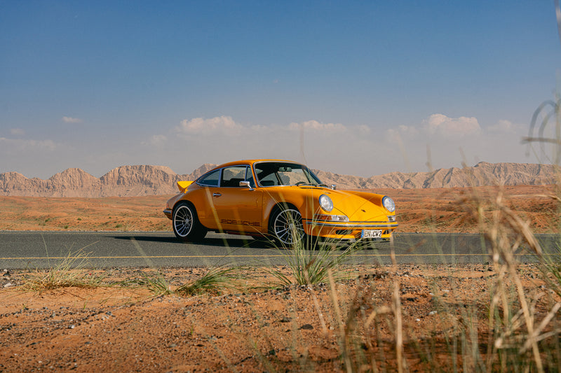 Yellow Triebwerk F4.3 Porsche 911 on a road with a desert landscape