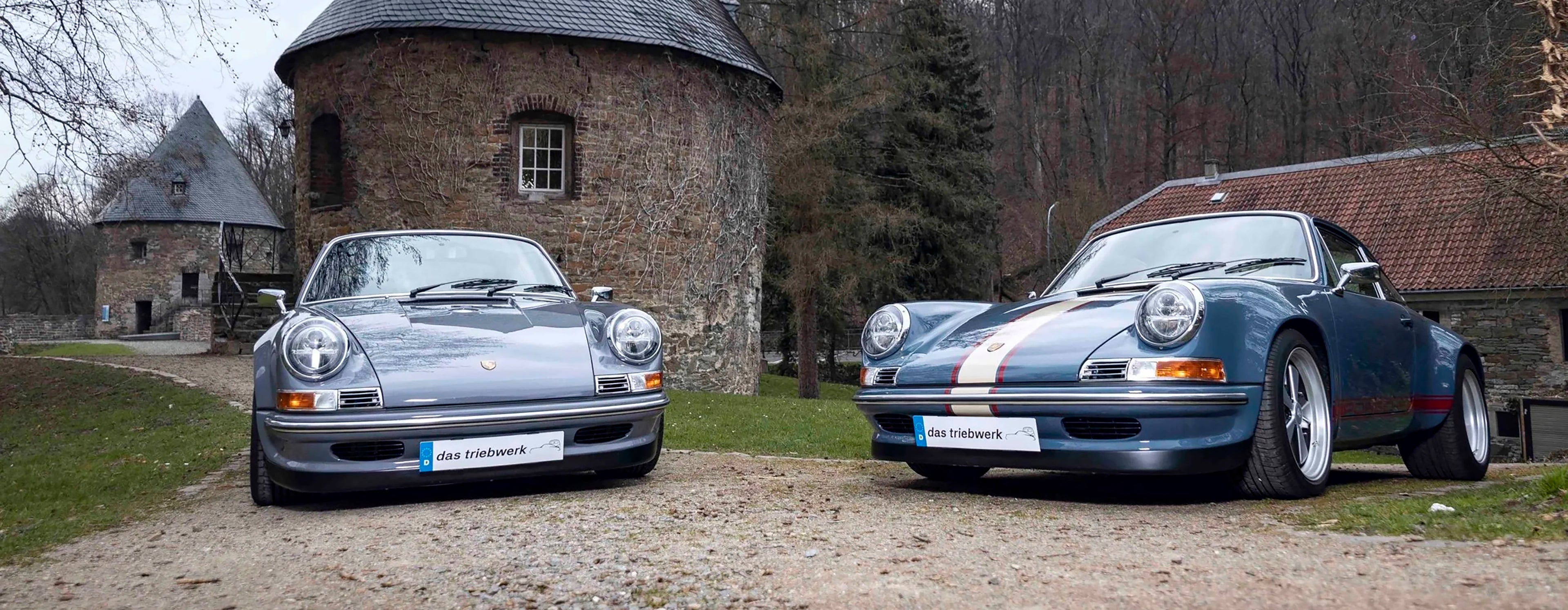 Two Triebwerk F350 and F3.8 parked in front of a stone building with trees in the background