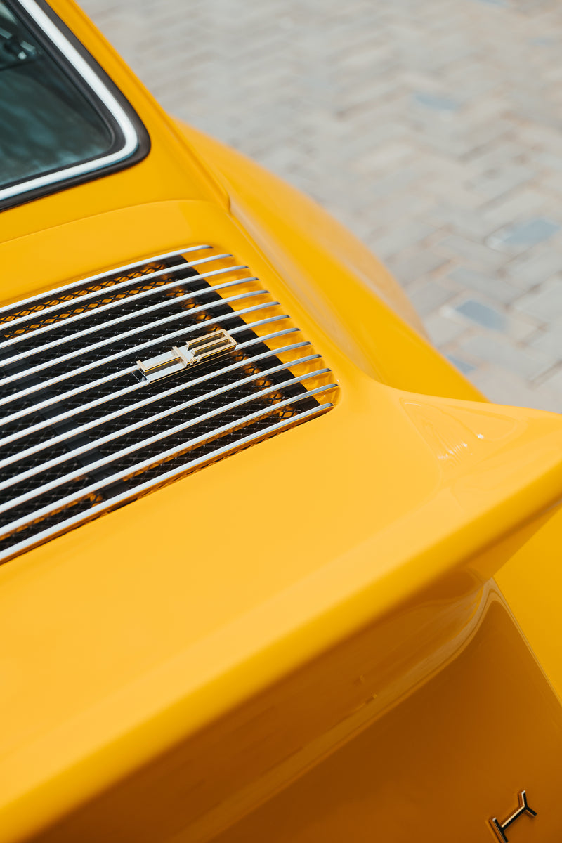 Close-up of a Yellow Triebwerk F4.3 Porsche 911 engine grille with 4.3 badge.