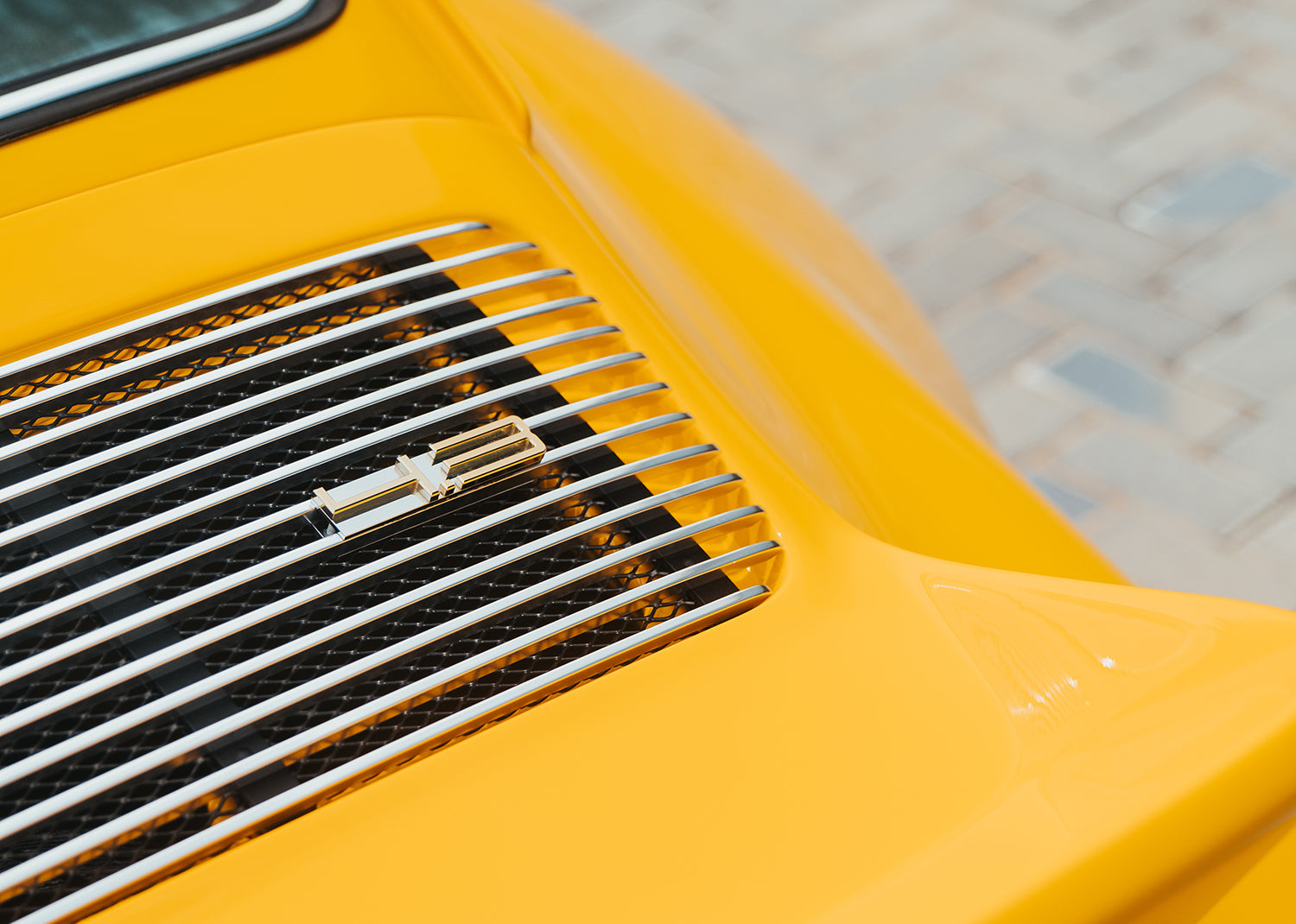 Close-up of a Yellow Triebwerk F4.3 Porsche 911 engine grille with a 4.3 badge.