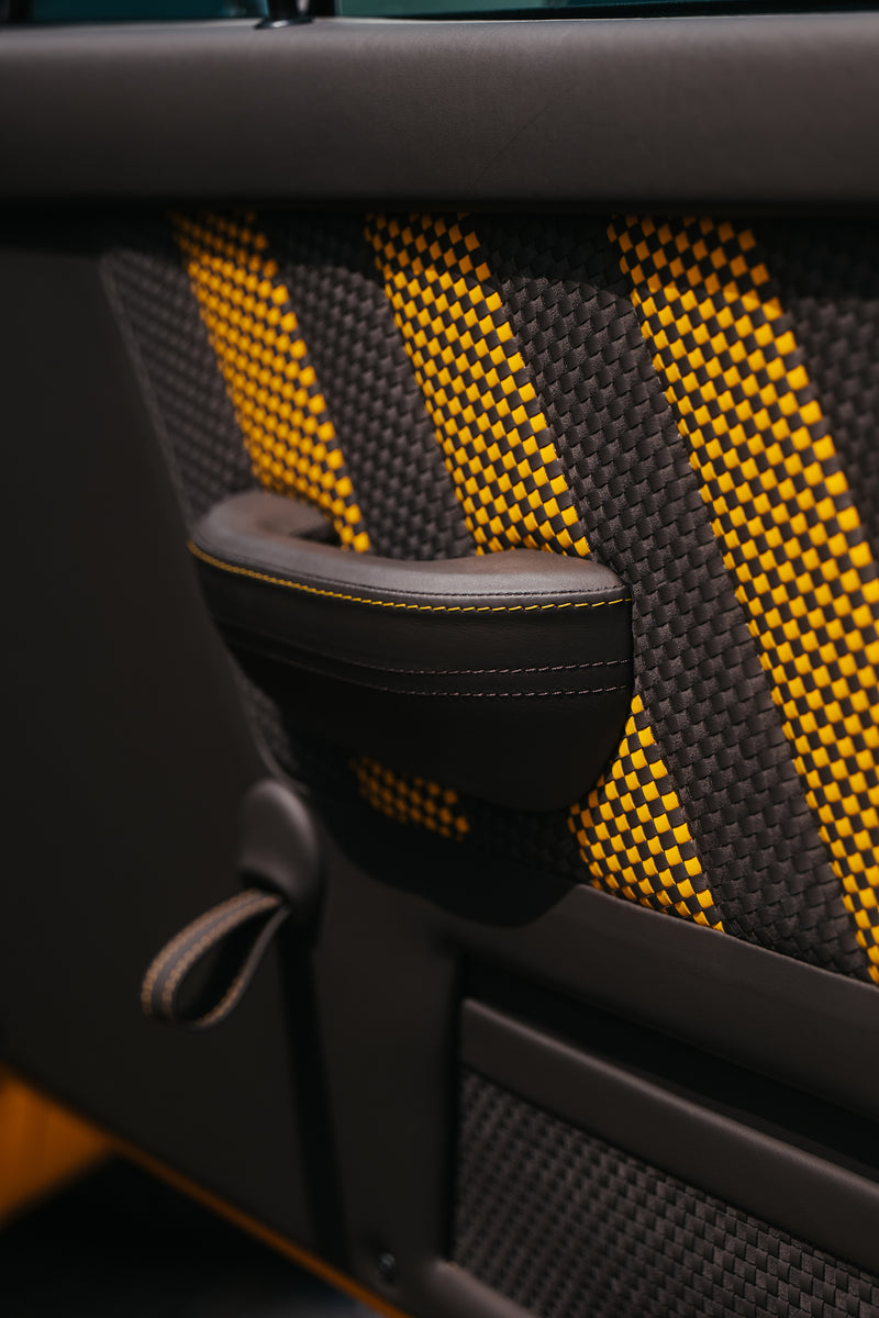 Close-up of Yellow Triebwerk F4.3 Porsche 911 door handle with a black and yellow patterned interior.