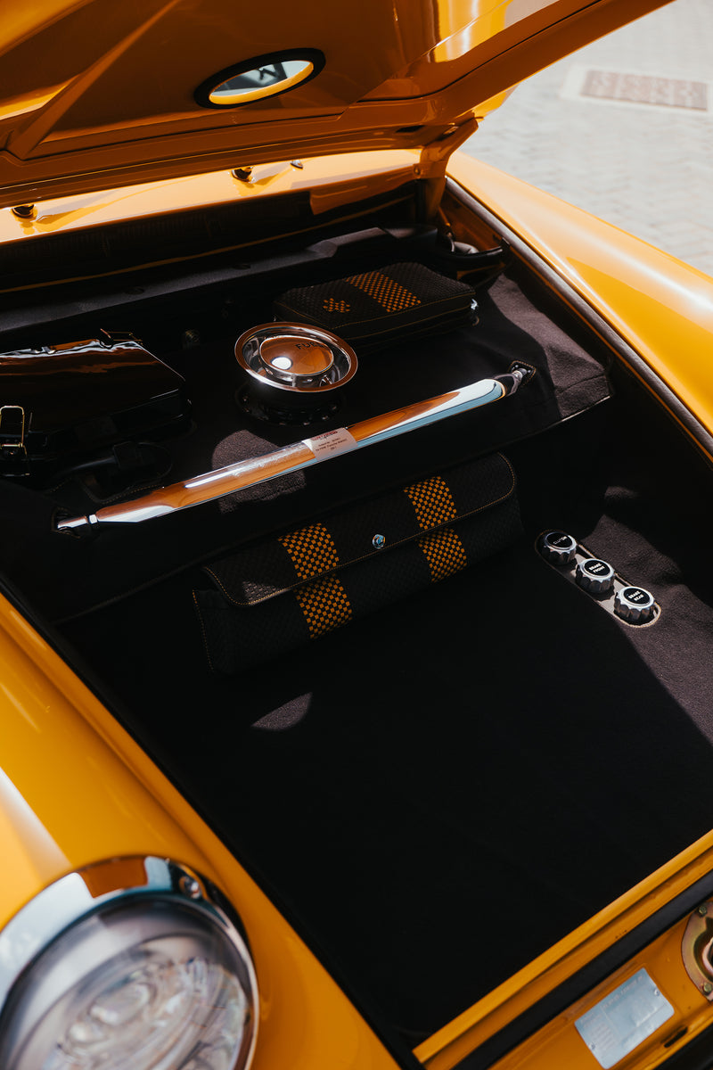 Close-up of a Yellow Triebwerk F4.3 Porsche 911 open frunk with a black interior.