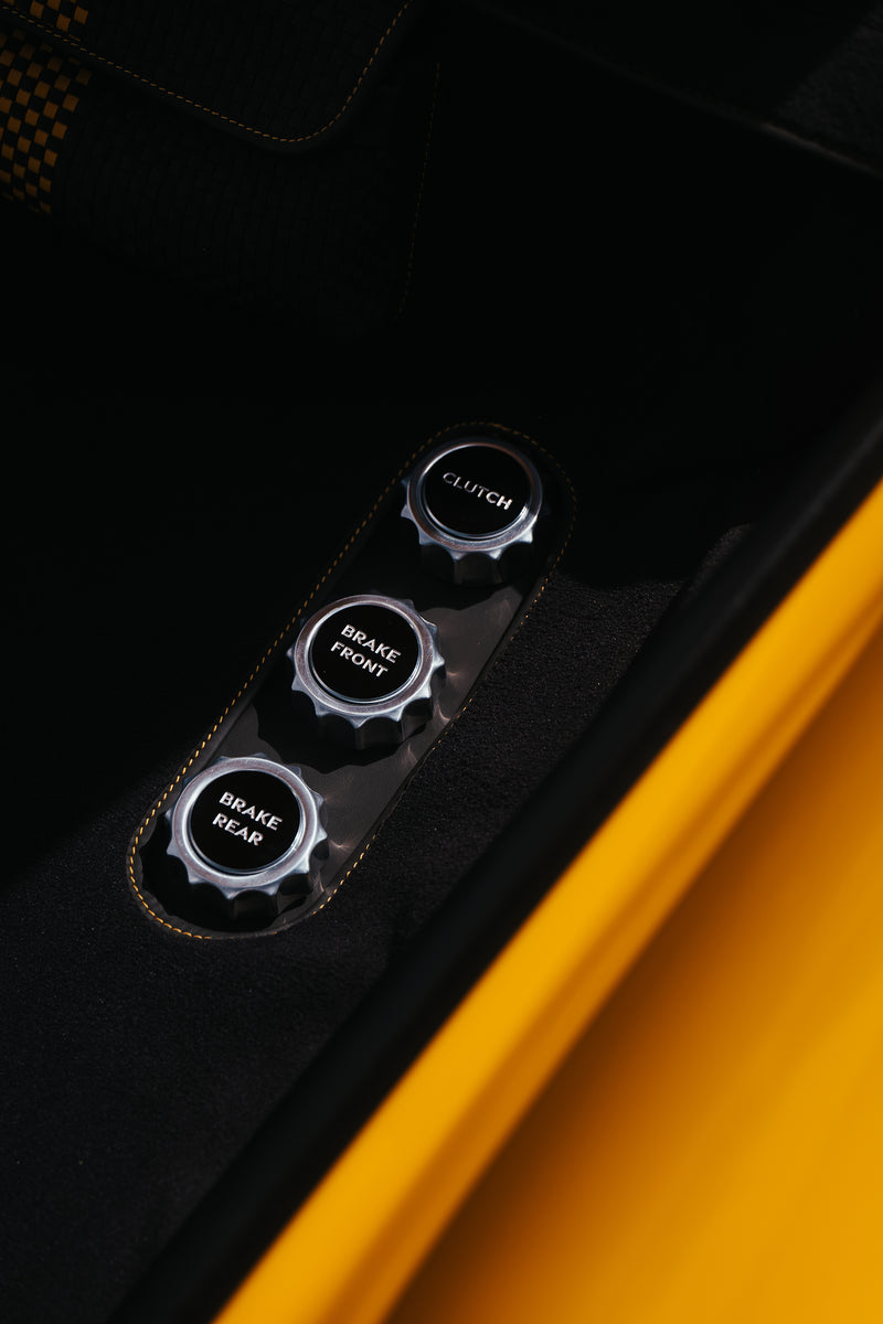 Close-up of a Yellow Triebwerk F4.3 Porsche 911 'Drive', 'Brake', and 'Clutch' knobs.
