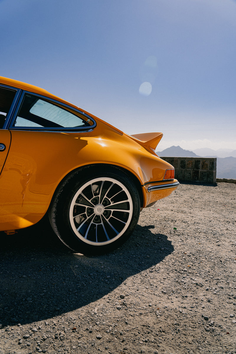 Yellow Triebwerk F4.3 Porsche 911 on a dirt road with a clear blue sky