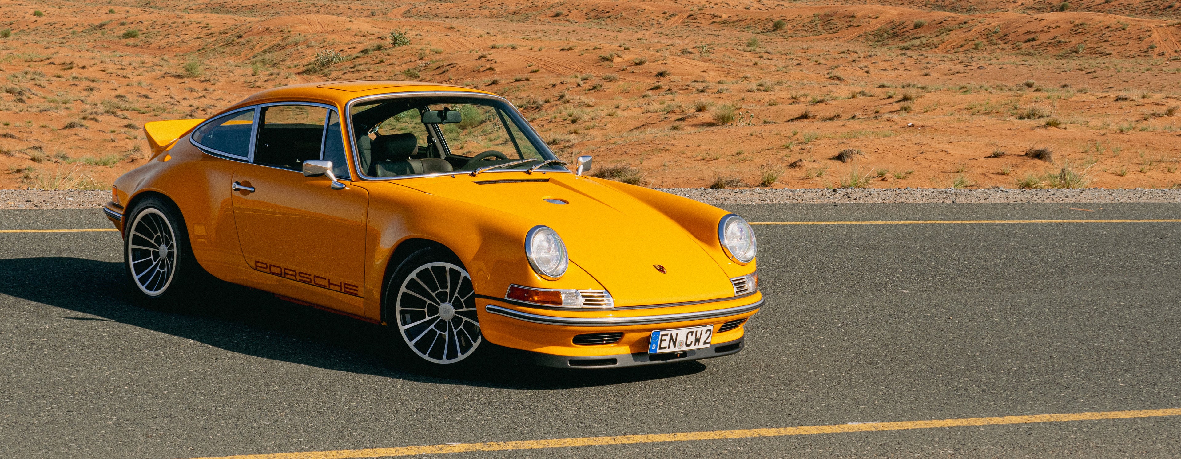 Yellow Triebwerk F4.3 Porsche 911 on a road with a desert landscape