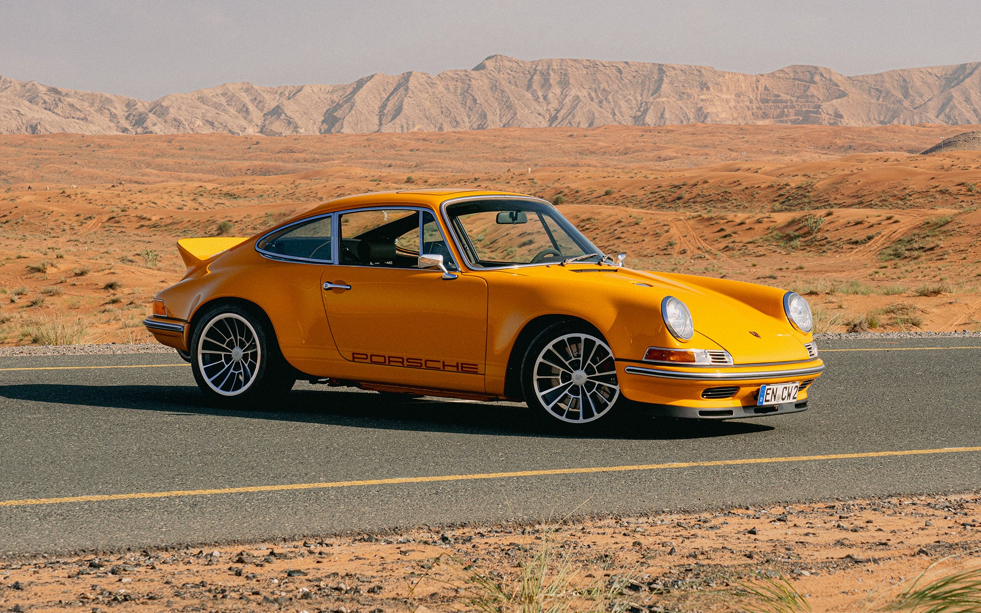 Yellow Triebwerk F4.3 Porsche 911 on a road with a desert landscape