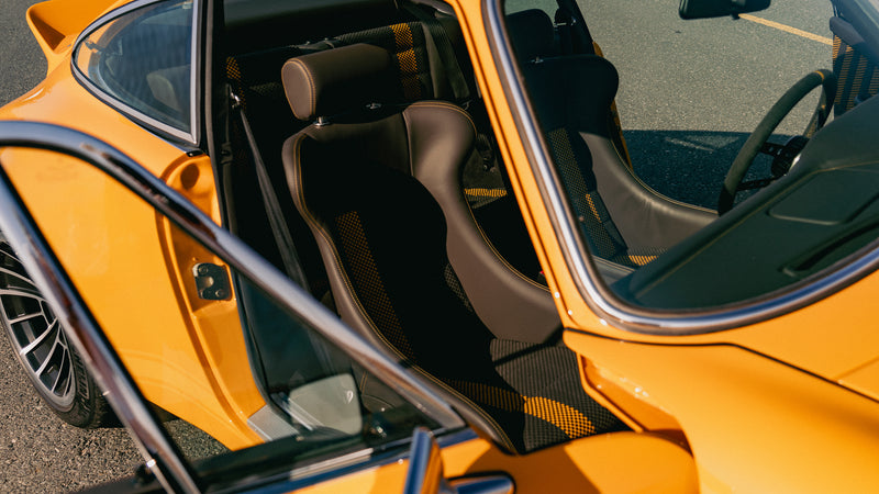 Close-up of a Yellow Triebwerk F4.3 Porsche 911 with open door, showing interior.
