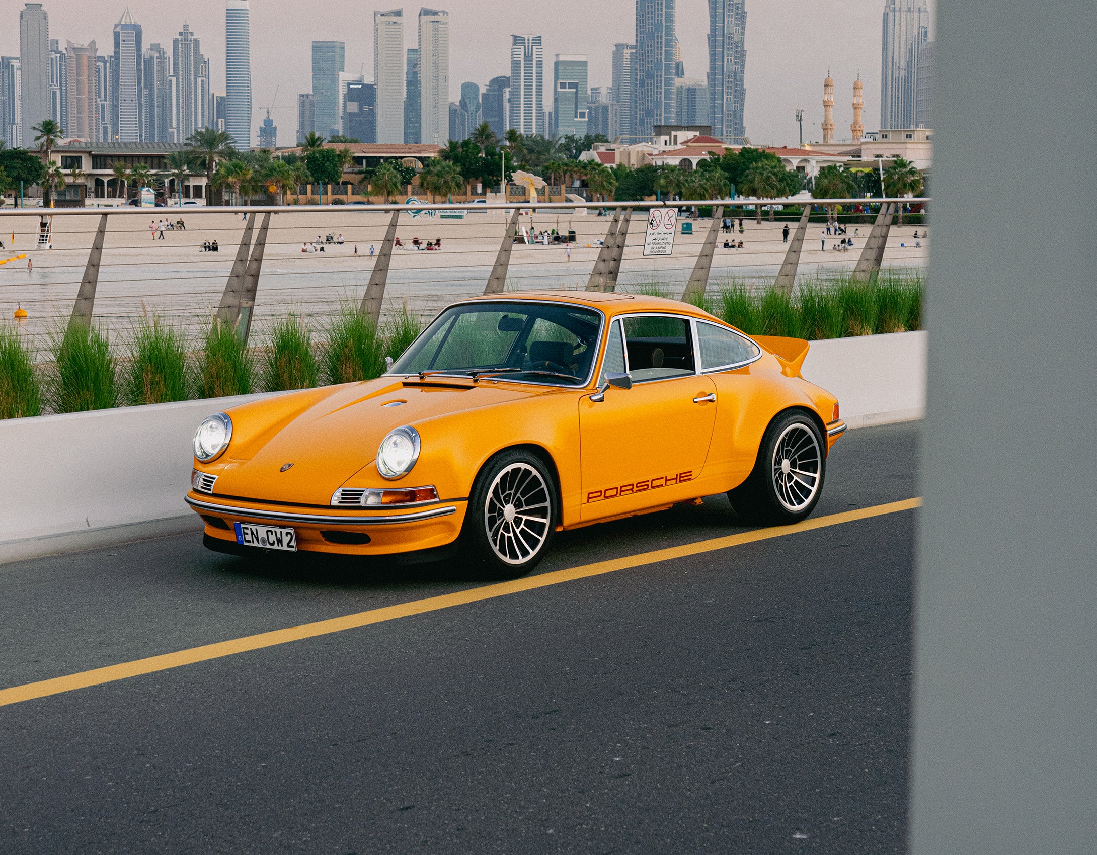 Yellow Triebwerk F4.3 Porsche 911 on a road with Dubai city skyline in the background
